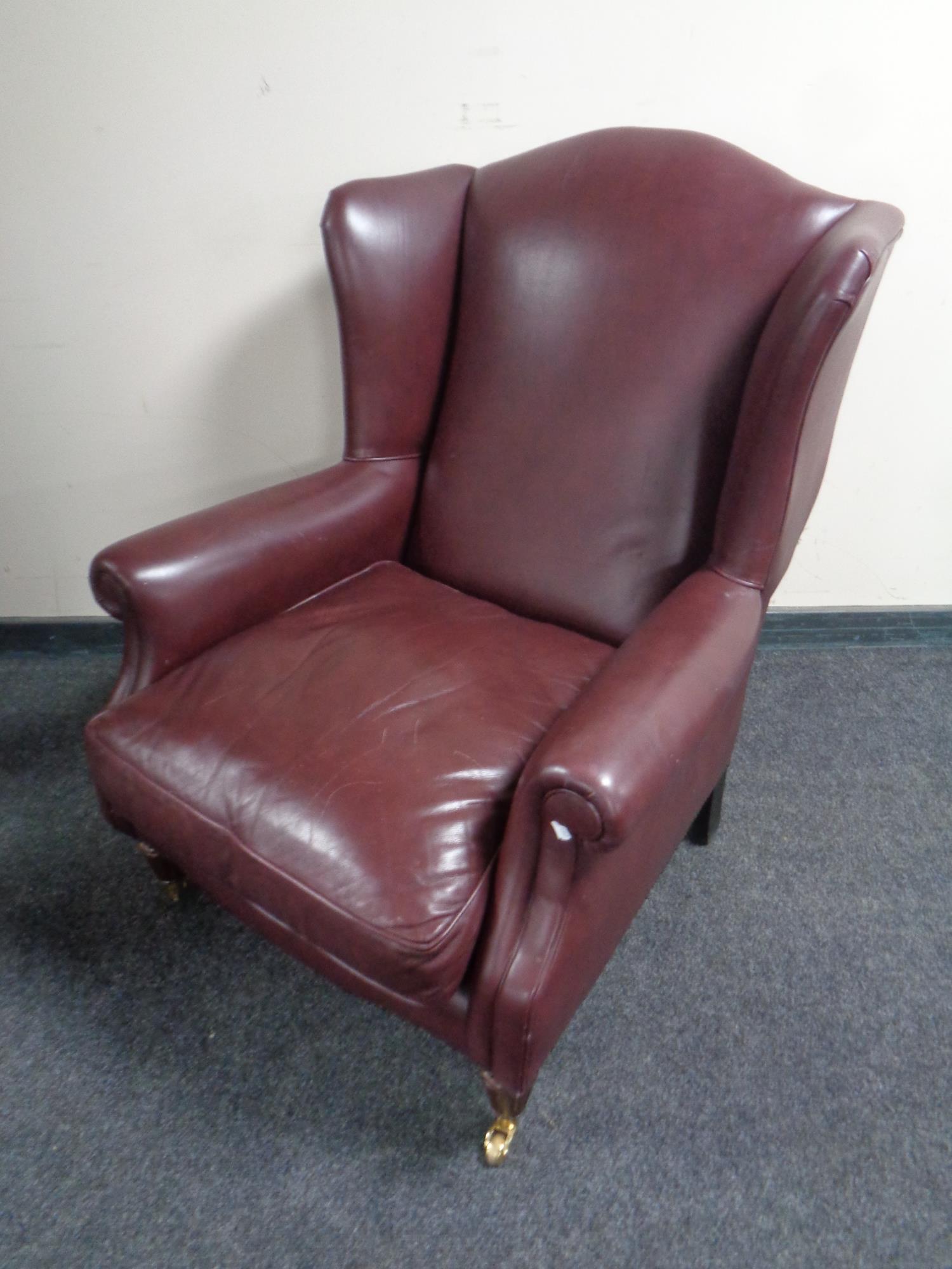 A wingback armchair upholstered in maroon leather