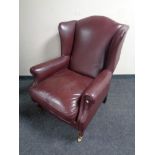 A wingback armchair upholstered in maroon leather