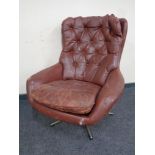 A mid 20th century buttoned leather upholstered armchair on swivel base