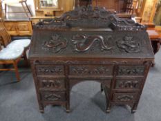 A finely carved Indonesian fall front writing bureau with fitted interior fitted seven drawers