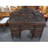 A finely carved Indonesian fall front writing bureau with fitted interior fitted seven drawers