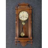 An Edwardian carved oak eight day wall clock with pendulum