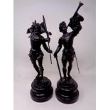 A pair of painted spelter figures on circular wooden bases