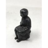 An early 19th century iron figure modelled as a child seated on a chamber pot, height 8 cm.
