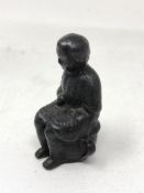 An early 19th century iron figure modelled as a child seated on a chamber pot, height 8 cm.