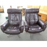 A pair of brown leather swivel reclining armchairs on chrome bases