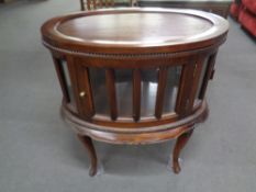 An oval drinks cabinet on raised legs with lift off tray