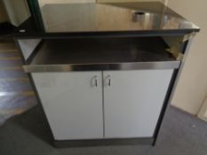 A marble top commercial double door storage cupboard containing cardboard drinks trays,