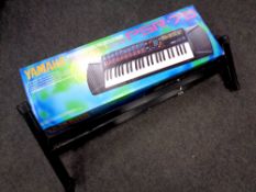A Yamaha Portatone PSR76 electric keyboard in box together with a folding keyboard stand