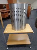 A metal and wood two tier serving trolley together with a contemporary laundry bin