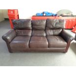 A brown leather upholstered three-seater settee