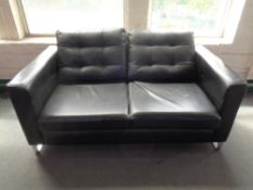 A black leather upholstered two-seater settee on chrome legs