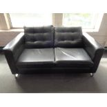 A black leather upholstered two-seater settee on chrome legs