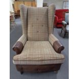 A contemporary high backed fireside chairs in a two tone leather and cloth fabric,