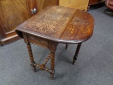 An Edwardian carved oak flap sided table on barley twist legs