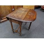 An Edwardian carved oak flap sided table on barley twist legs