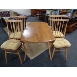 An Ercol elm and beech drop leaf dining room table and four stick back armchairs