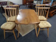 An Ercol elm and beech drop leaf dining room table and four stick back armchairs