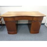 An early 20th century serpentine fronted twin-pedestal desk