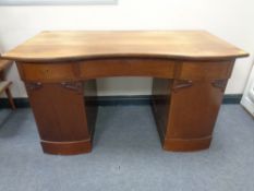 An early 20th century serpentine fronted twin-pedestal desk