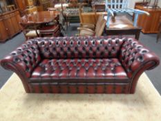 A good Chesterfield oxblood buttoned leather three seater scroll arm settee
