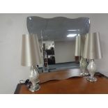 A shaped all glass mirror and a pair of contemporary table lamps