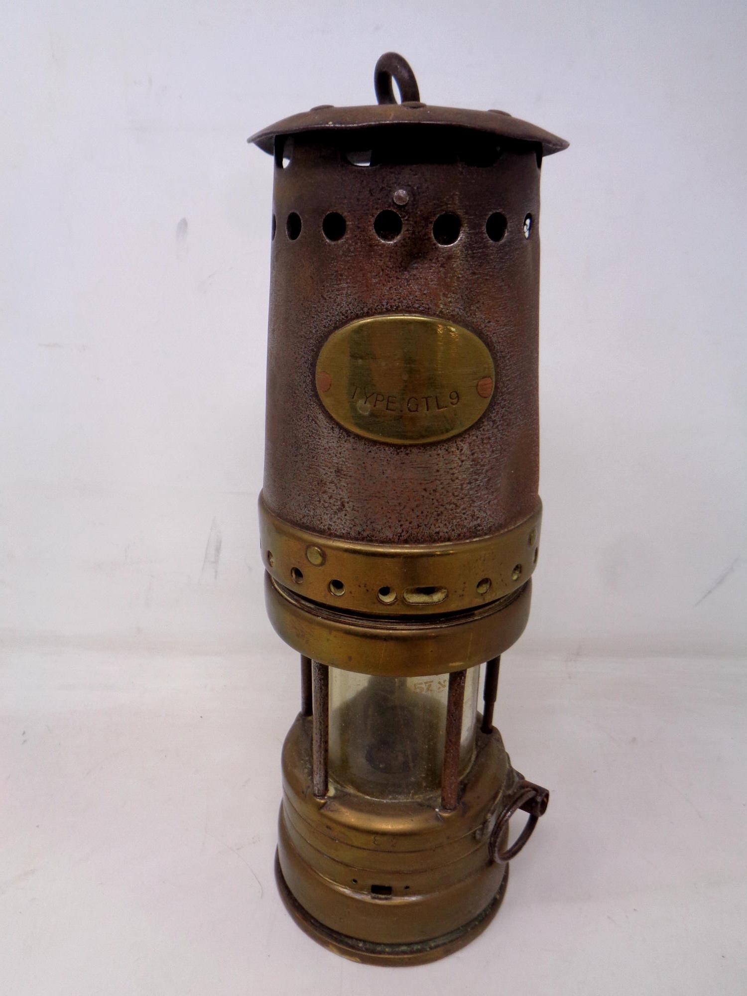 An antique steel and brass miner's lamp.