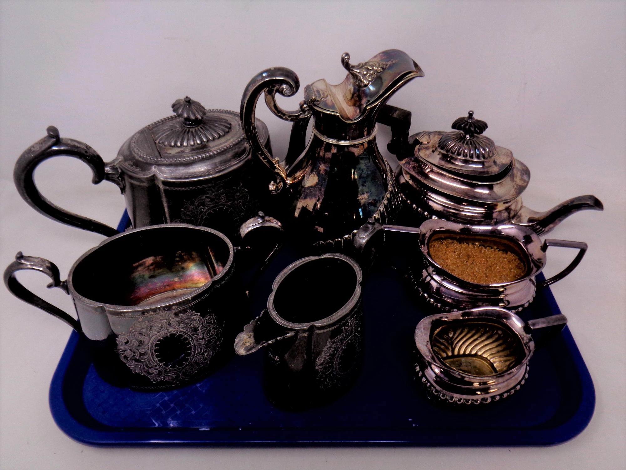 A tray of two silver plated tea sets and a further water jug