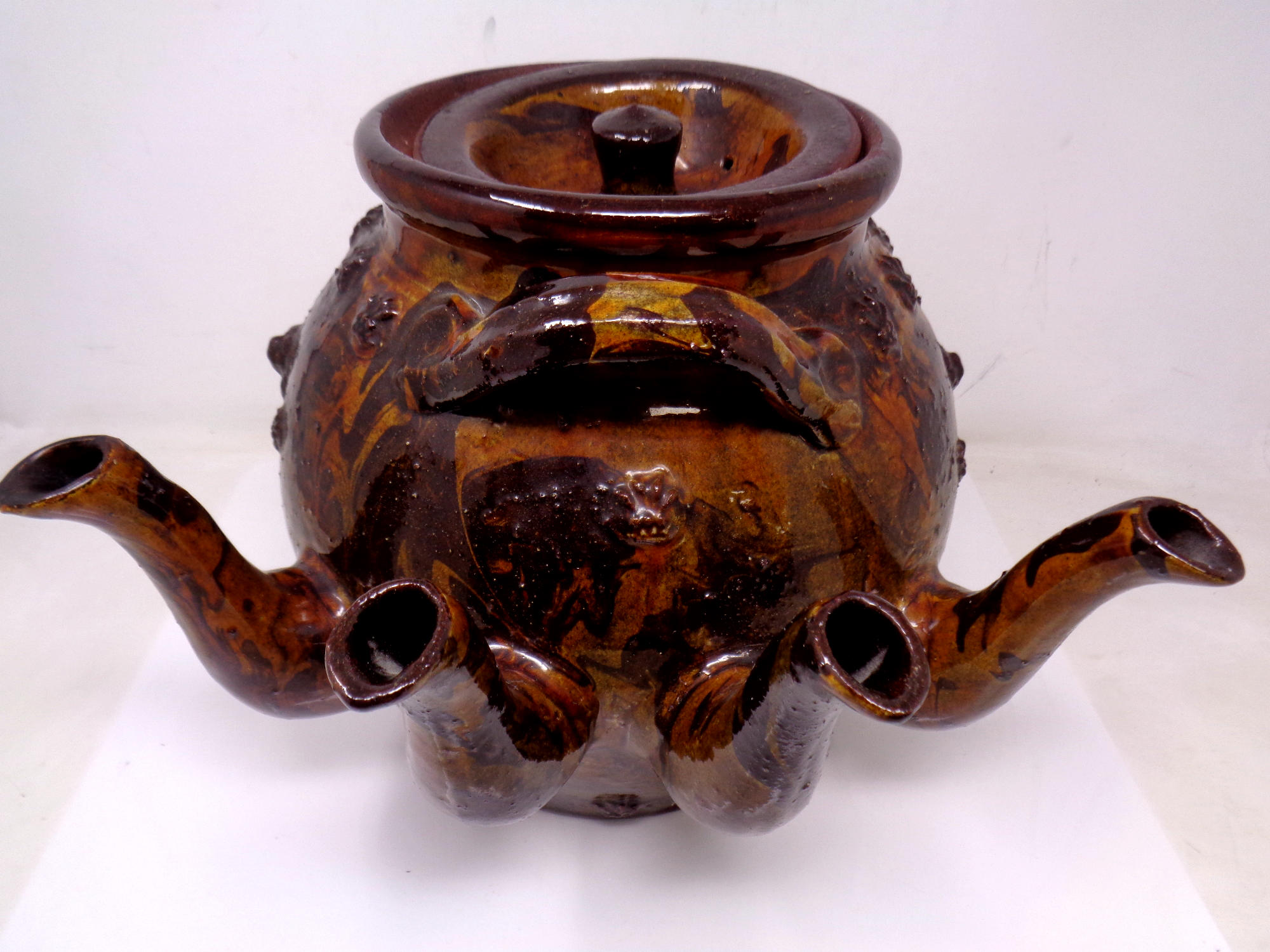 A very large folk art slipware four spouted stone ware teapot with applied decoration of lions and