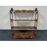A mahogany four tier wall shelf fitted three drawers beneath