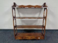 A mahogany four tier wall shelf fitted three drawers beneath
