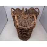 Three glazed stoneware bottles encased in wicker carriers