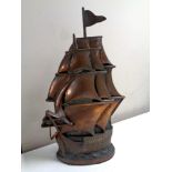 A copper and cast iron hearth companion set in the form of a galleon, complete with brush and tongs.