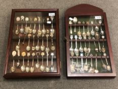 A glazed wall-hanging display cabinet containing twenty nine miscellaneous souvenir spoons,