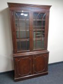 A mahogany double door glazed bookcase fitted cupboards beneath