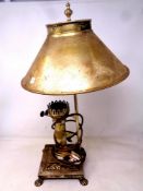A brass retro style table lamp in the form of an oil lamp on paw feet.