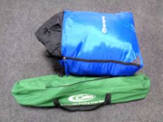 A folding camp bed together with a bag of sleeping bags
