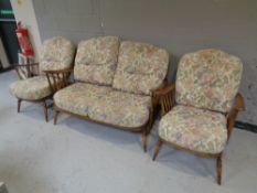 An Ercol beech three piece suite : two seater settee and a pair of armchairs