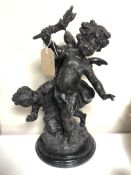 A cast bronze figure of a cherub holding a torch with a girl at his feet, height 44 cm.