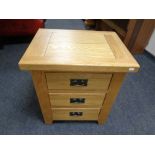 An oak three drawer bedside chest