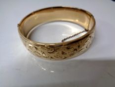 An engraved gold plated hinged bangle