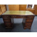 A mahogany twin pedestal writing desk fitted nine drawers with green tooled leather inset panel