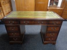 A mahogany twin pedestal writing desk fitted nine drawers with green tooled leather inset panel