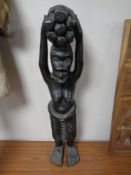 A 20th century African carved hardwood statue of a figure carrying fire wood,