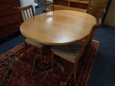 A 20th century teak G-Plan oval extending dining table together with a set of four rail back chairs