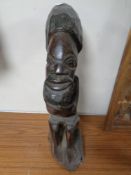 A 20th century African carved hardwood statue of a seated man,