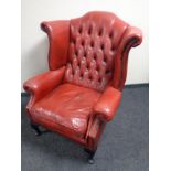 A Chesterfield red buttoned leather wingback armchair