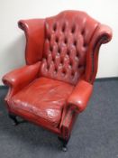 A Chesterfield red buttoned leather wingback armchair