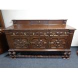 An Edwardian oak three door three drawer sideboard on a raised barley twist base