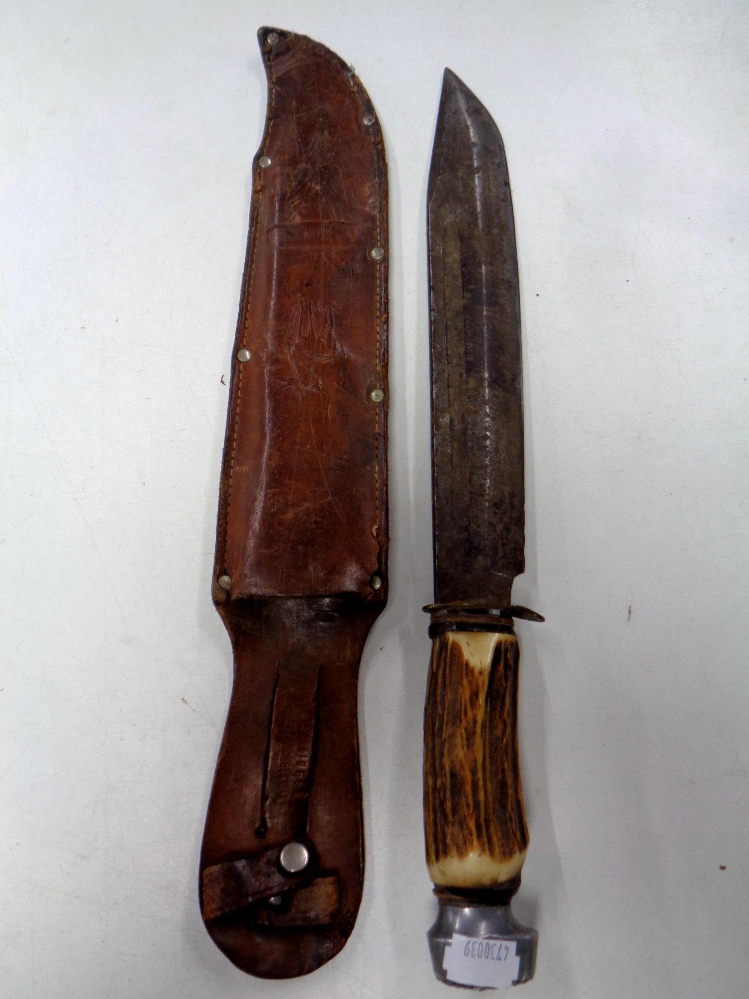 A Bowie style knife with antler grip in leather sheath